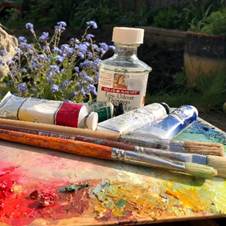 Paint brushes and tubes of paint on a palette  Description automatically generated